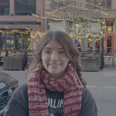 Laurel smiling on a downtown street strung with lights